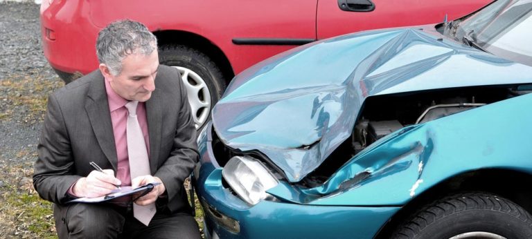 An insurance adjustor evaluating the damage of a wrecked car.
